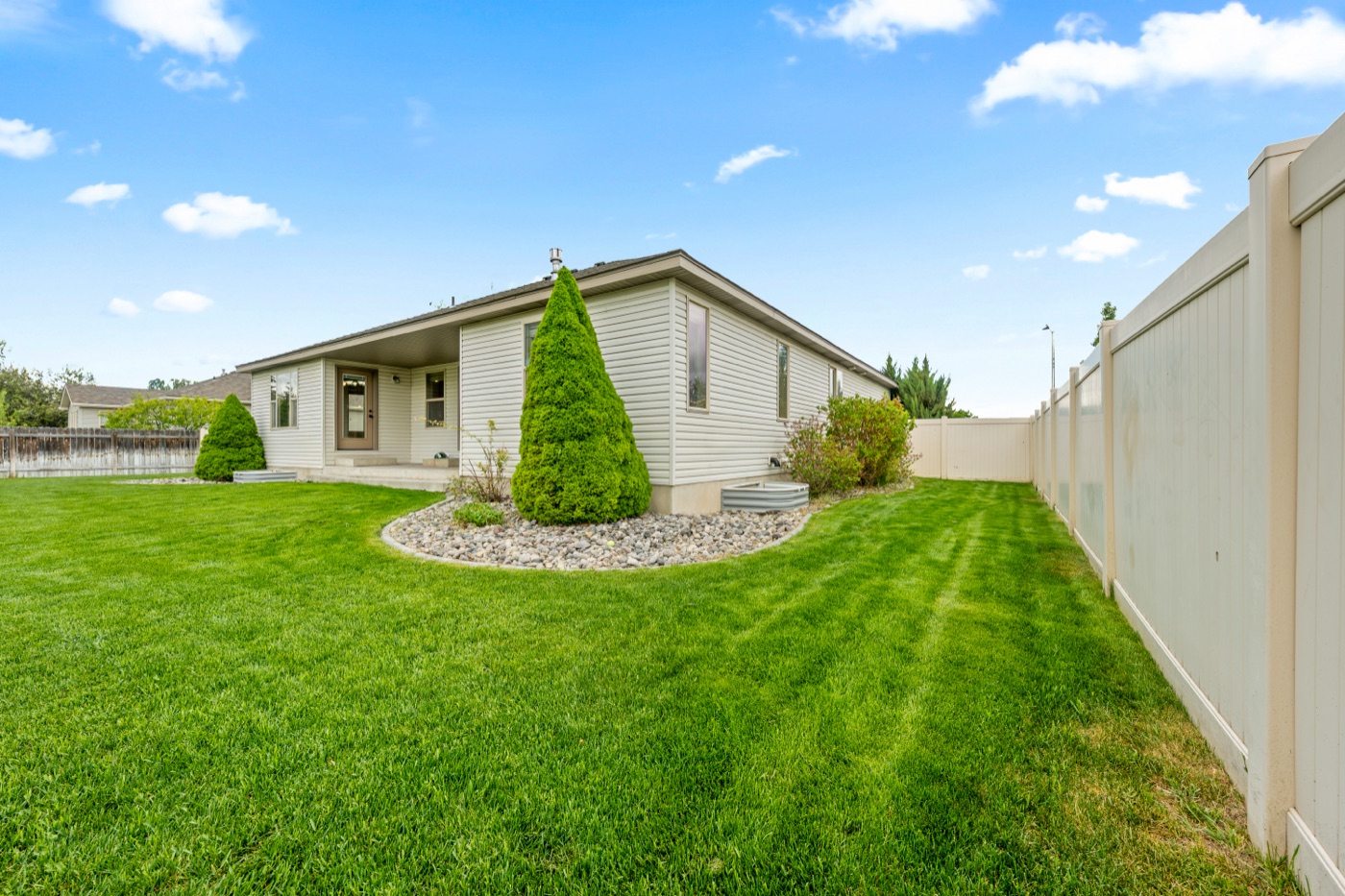 Yard corner with mature trees and vinyl fence